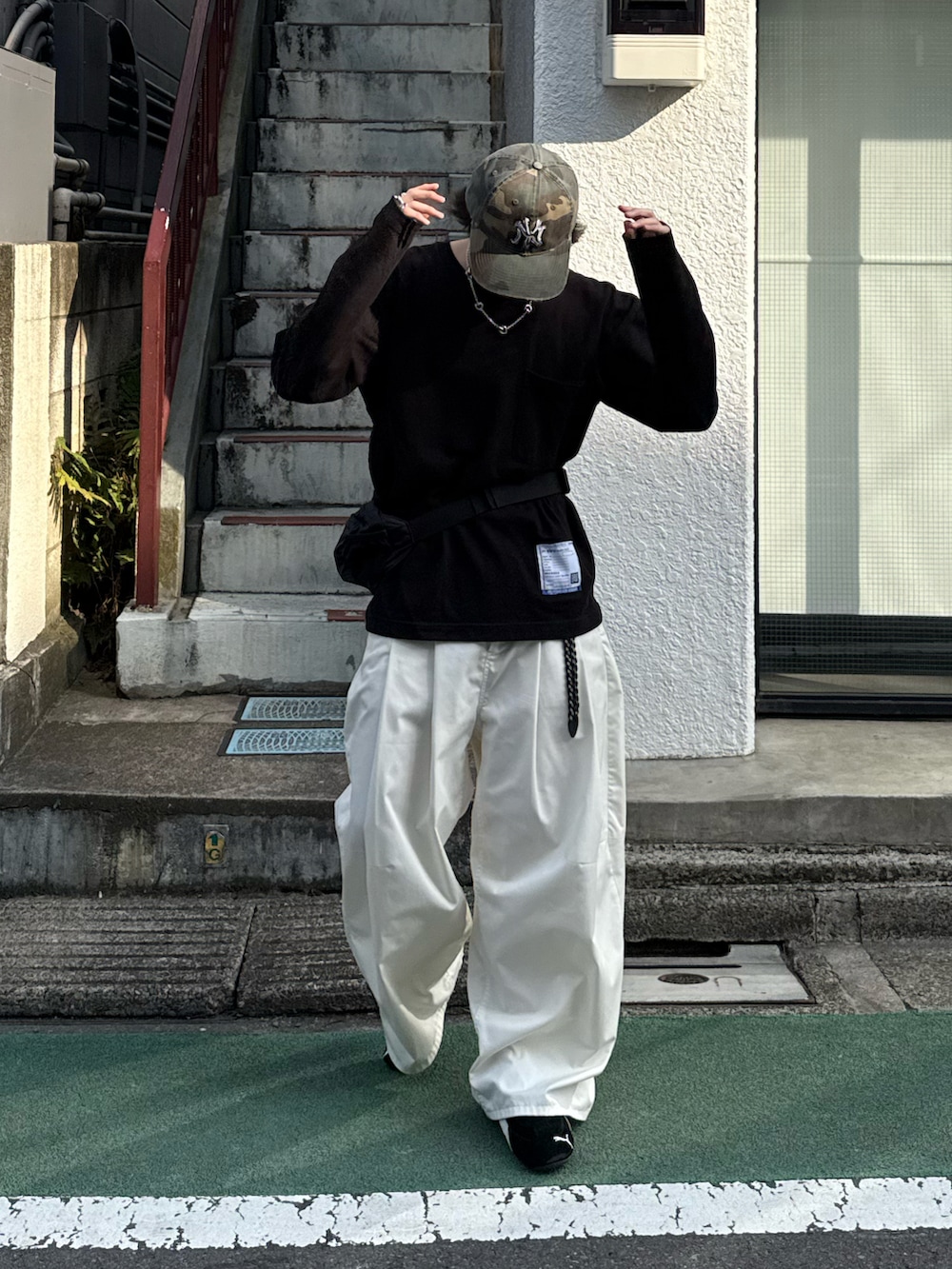 ブラック系のTシャツ/カットソー、ホワイト系のその他パンツ、ブラック系のボディバッグ/ウエストポーチを着用したメンズの春コーディネートの2枚目の写真