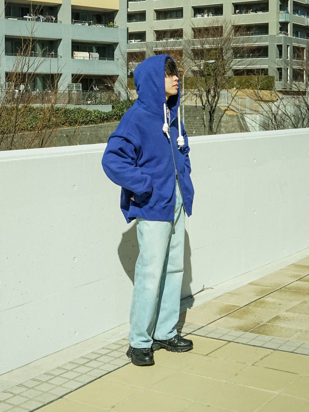 ブルー系のパーカー、ブルー系のデニムパンツ、ブラック系のスニーカーを着用したメンズの冬コーディネートの2枚目の写真