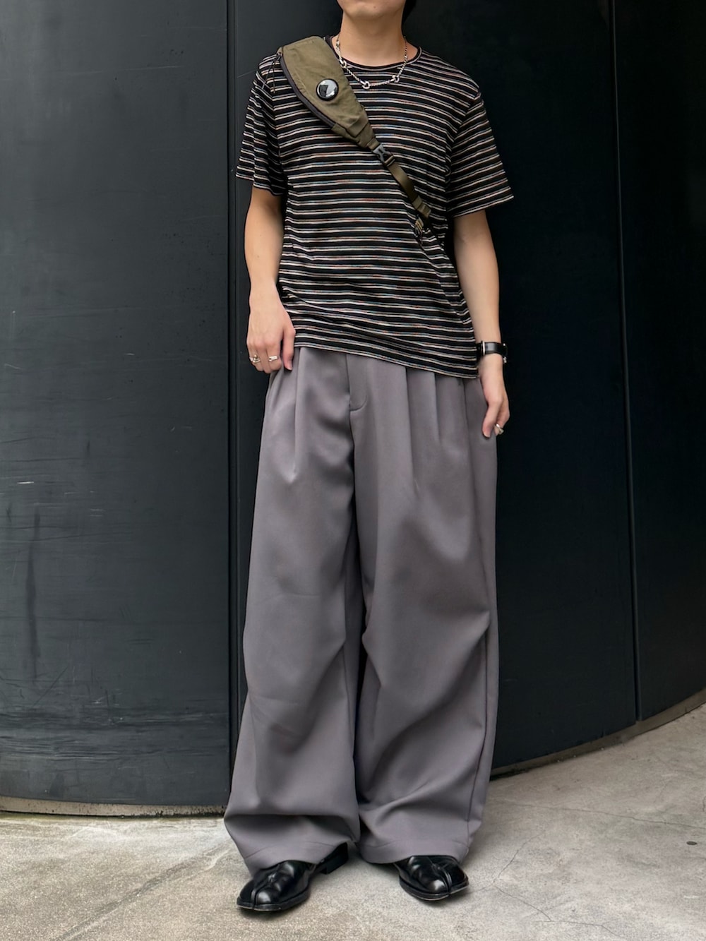 ブラック系のTシャツ/カットソー、グレー系のパンツ、グリーン系のバックパック/リュックを着用したメンズの夏コーディネートの3枚目の写真