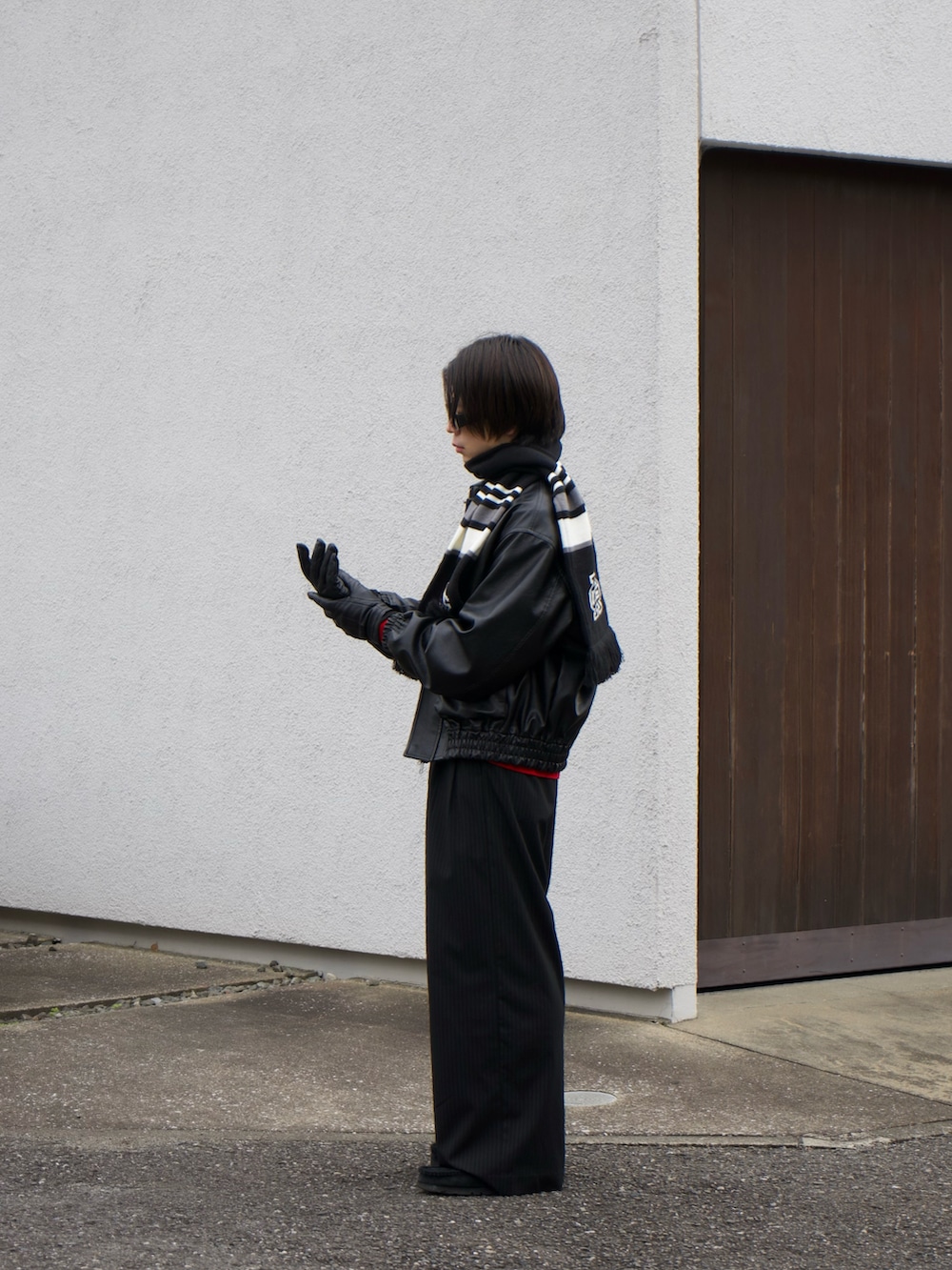 ブラック系のブルゾン、レッド系のニット/セーター、ブラック系のスラックスを着用したメンズの冬コーディネートの3枚目の写真