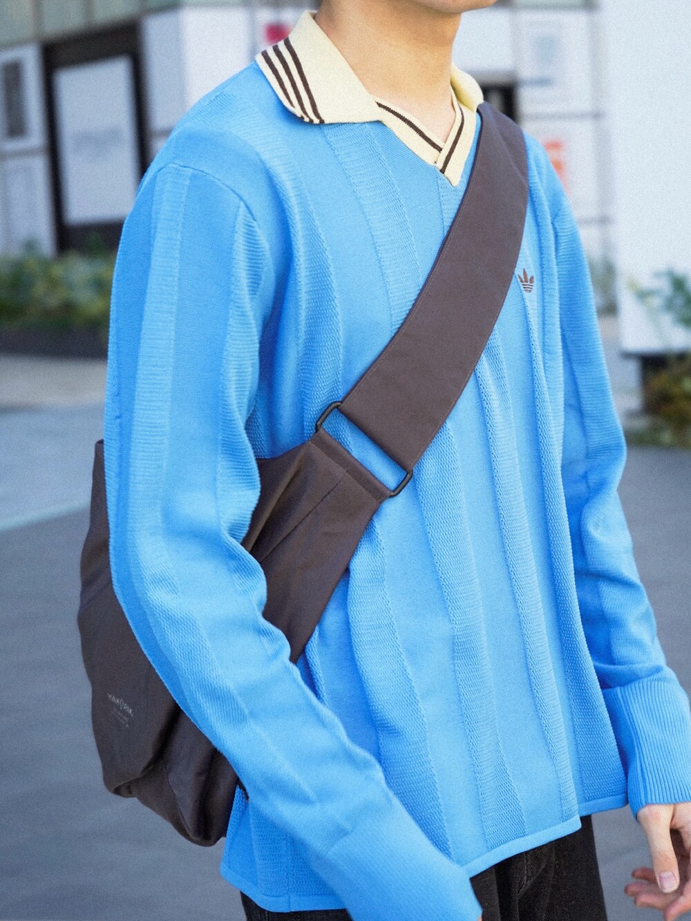 ブルー系のニット/セーター、ブラック系のデニムパンツ、グレー系のショルダーバッグを着用したメンズの冬コーディネートの3枚目の写真