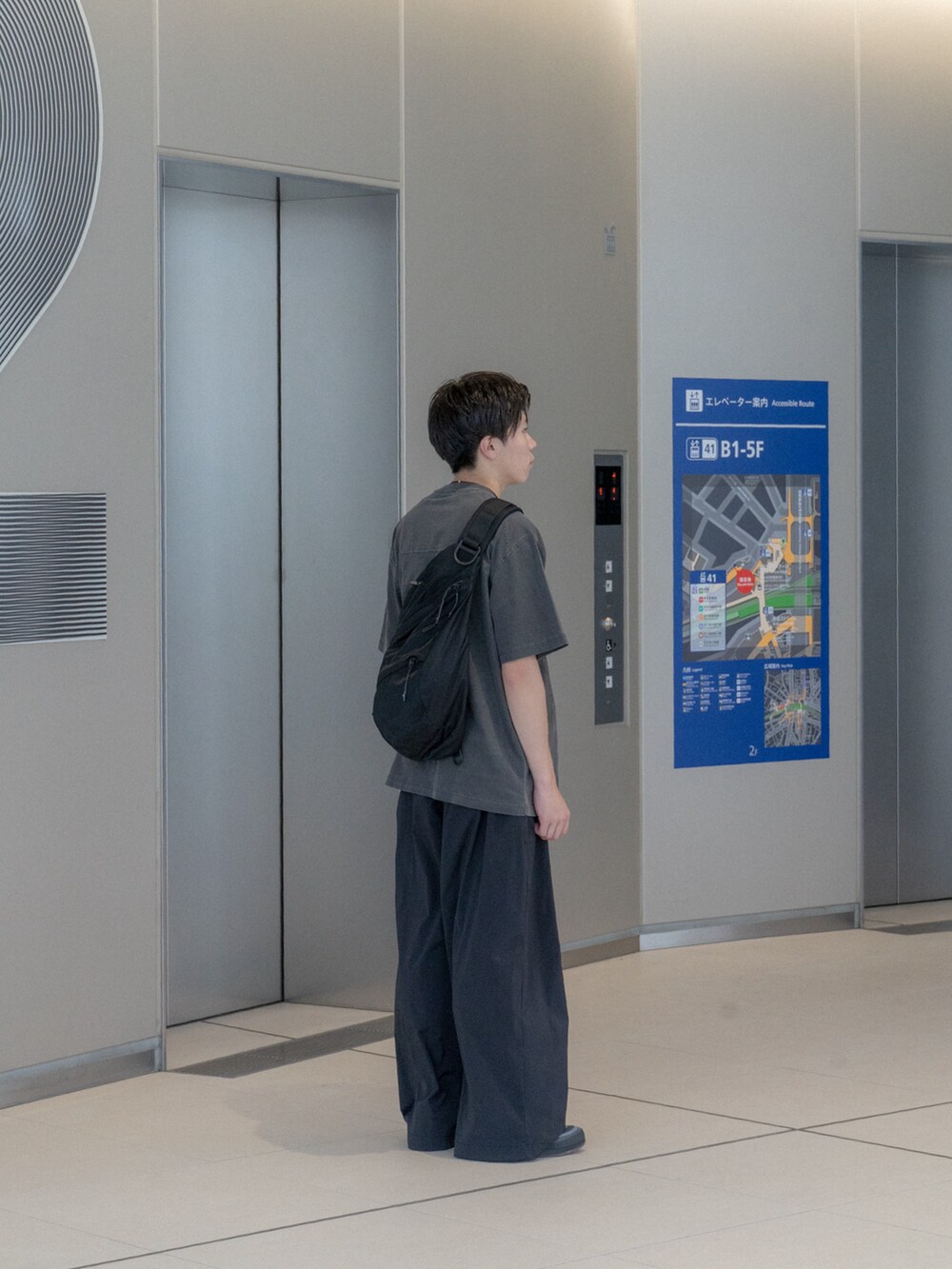 グレー系のTシャツ/カットソー、ブラック系のショルダーバッグ、ブラック系のスラックスを着用したメンズの夏コーディネートの3枚目の写真