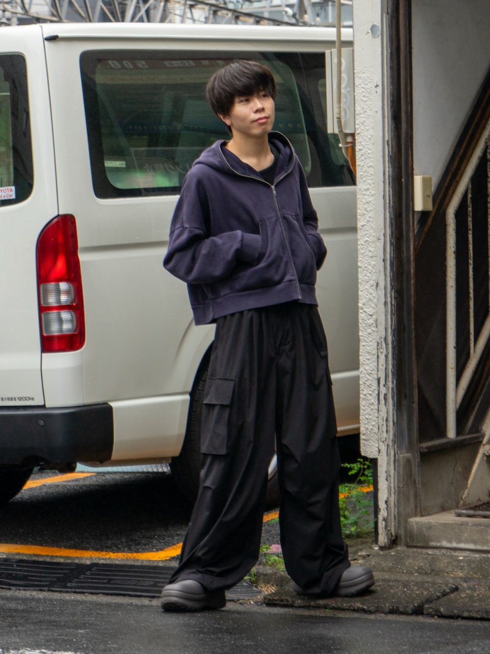 ブラック系のパーカー、ブラック系のカーゴパンツ、ブラウン系のサンダルを着用したメンズの秋コーディネートの2枚目の写真