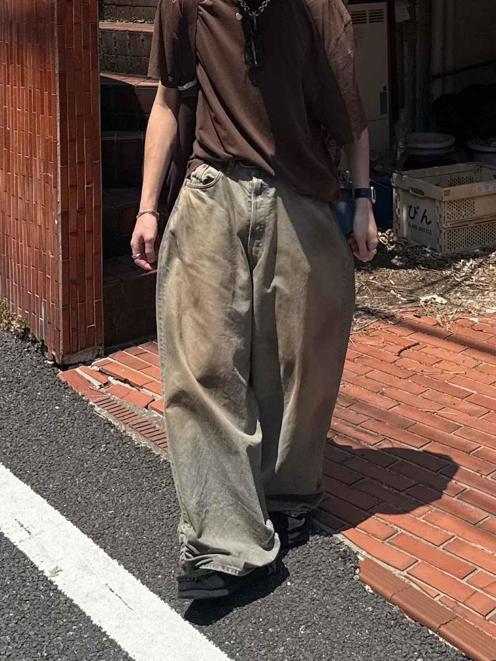 ブラウン系のTシャツ/カットソー、ブラウン系のトートバッグ、ブルー系のデニムパンツを着用したメンズの夏コーディネートの3枚目の写真