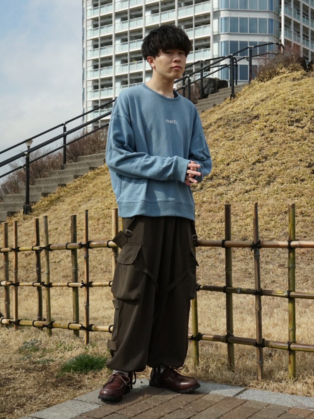 ブルー系のスウェット、グリーン系のサロペット/オーバーオール、ブラウン系のモカシン/デッキシューズを着用したメンズの冬コーディネートの3枚目の写真