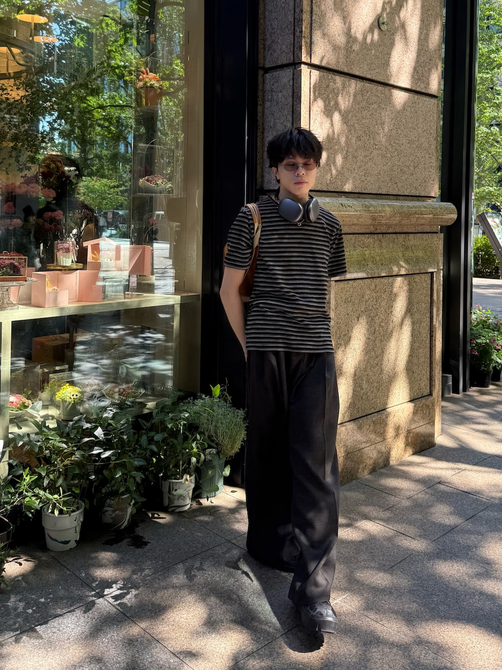 ブラック系のTシャツ/カットソー、ブラック系のスニーカー、ブラウン系のスラックスを着用したメンズの夏コーディネートの3枚目の写真