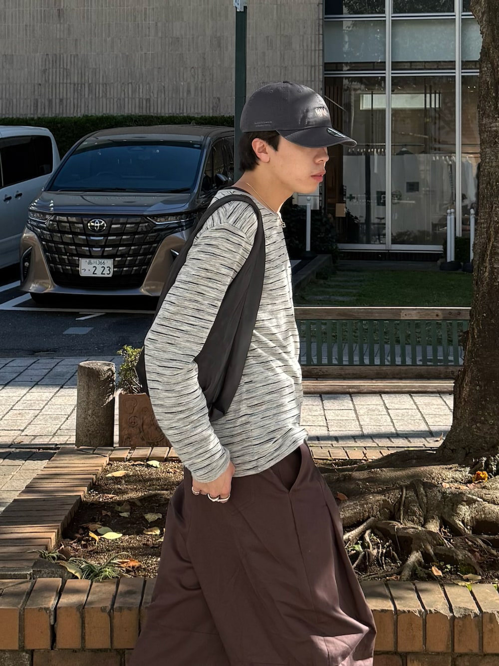 グレー系のTシャツ/カットソー、ブラウン系のその他パンツ、グレー系のハンドバッグを着用したメンズの秋コーディネートの3枚目の写真