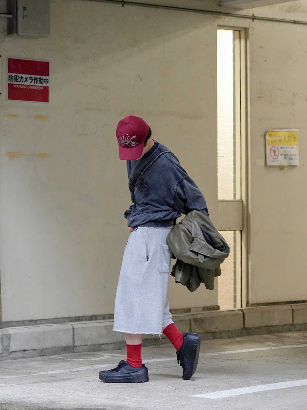 グレー系のスウェット、ブラック系のカバーオール、ブラウン系のショルダーバッグを着用したメンズの秋コーディネートの3枚目の写真