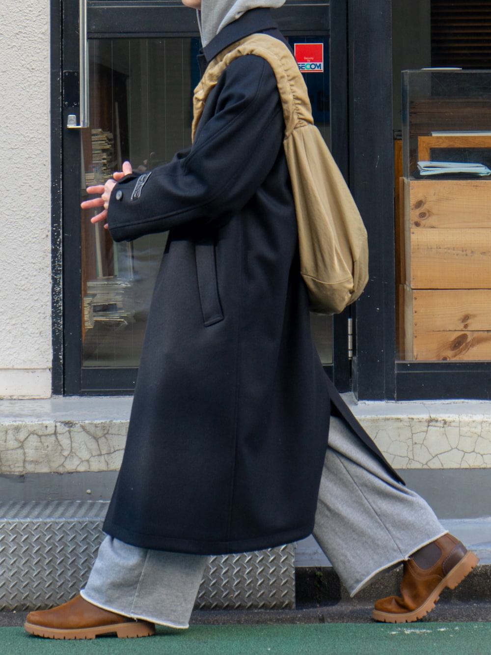 ブラック系のステンカラーコート、グレー系のスウェットパンツ、ベージュ系のショルダーバッグを着用したメンズの冬コーディネートの5枚目の写真