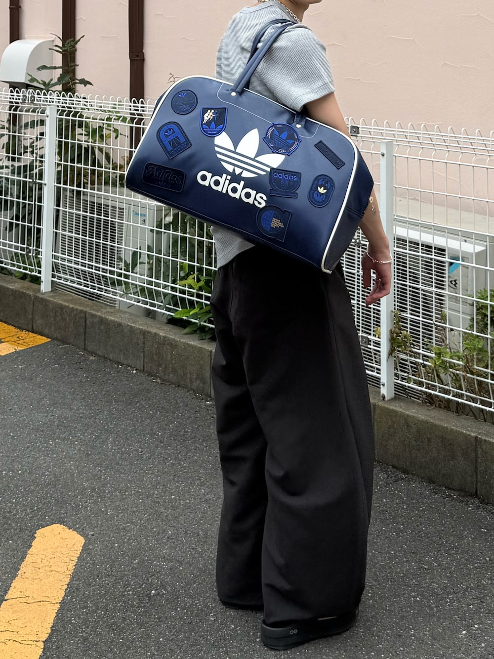 グレー系のTシャツ/カットソー、グレー系のスラックス、ブルー系のボストンバッグを着用したメンズの夏コーディネートの4枚目の写真