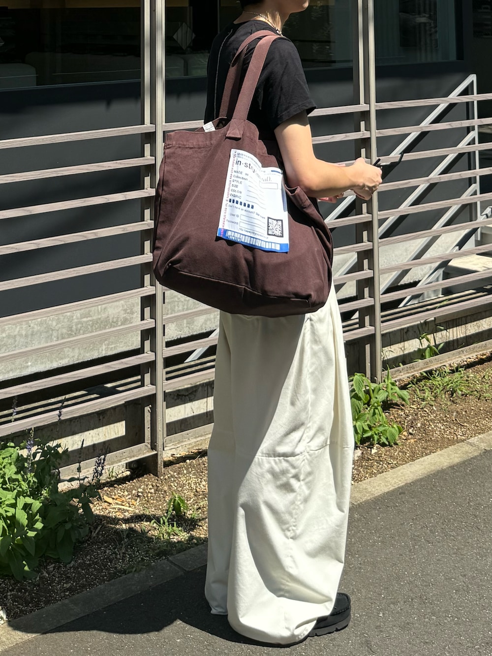 ホワイト系のその他パンツ、ブラウン系のトートバッグ、ブラック系のTシャツ/カットソーを着用したメンズの夏コーディネートの4枚目の写真
