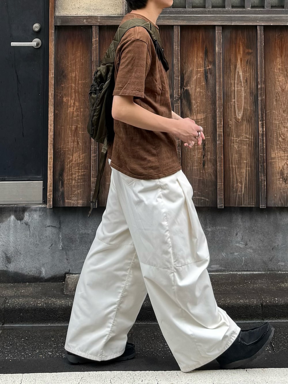 ブラウン系のTシャツ/カットソー、グリーン系のバックパック/リュック、ホワイト系のその他パンツを着用したメンズの秋コーディネートの4枚目の写真