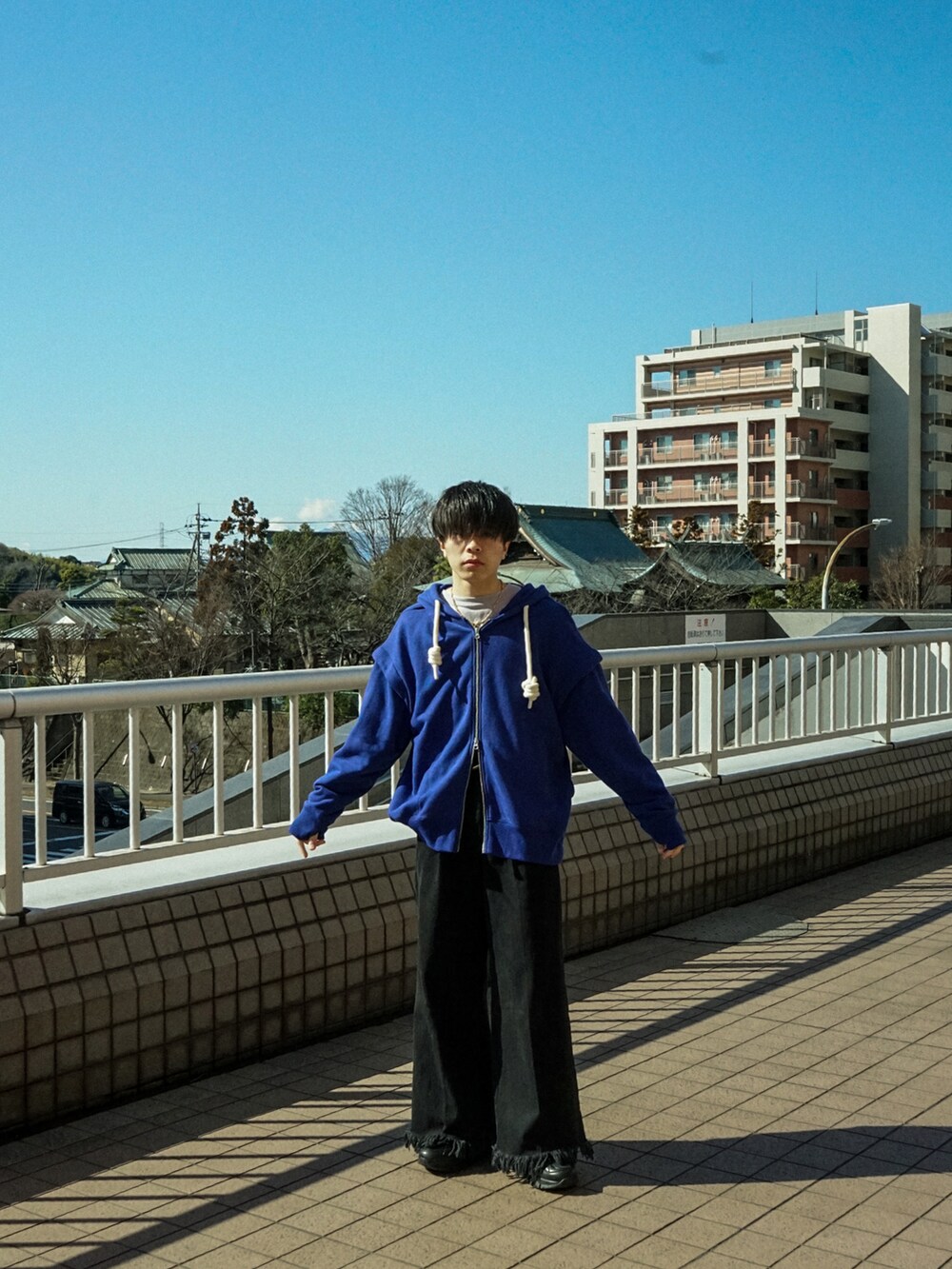 ブルー系のパーカー、ブラック系のデニムパンツ、ブラック系のスニーカーを着用したメンズの春コーディネートの3枚目の写真