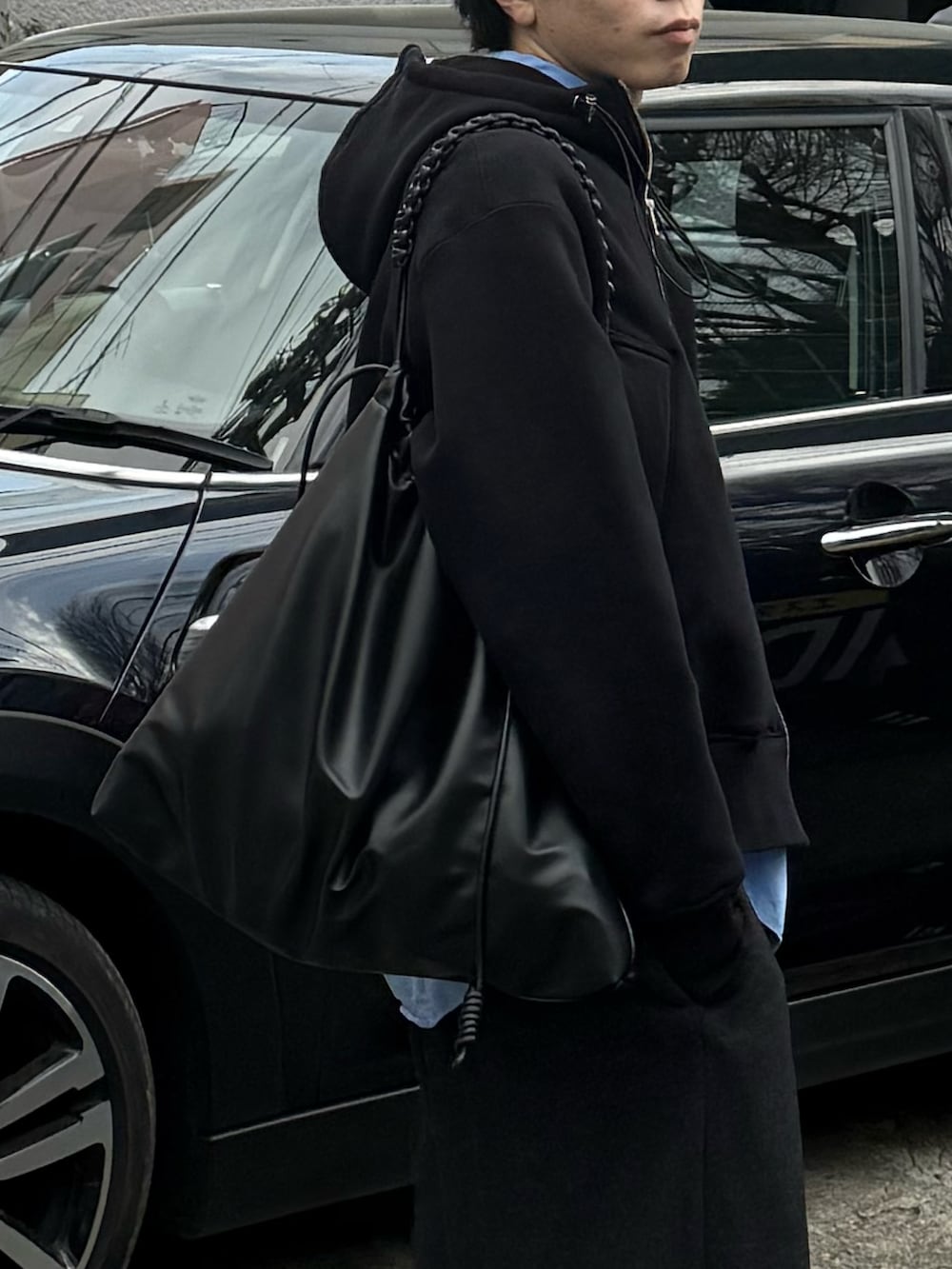 ブラック系のパーカー、グレー系のスラックス、ブラック系のショルダーバッグを着用したメンズの冬コーディネートの2枚目の写真