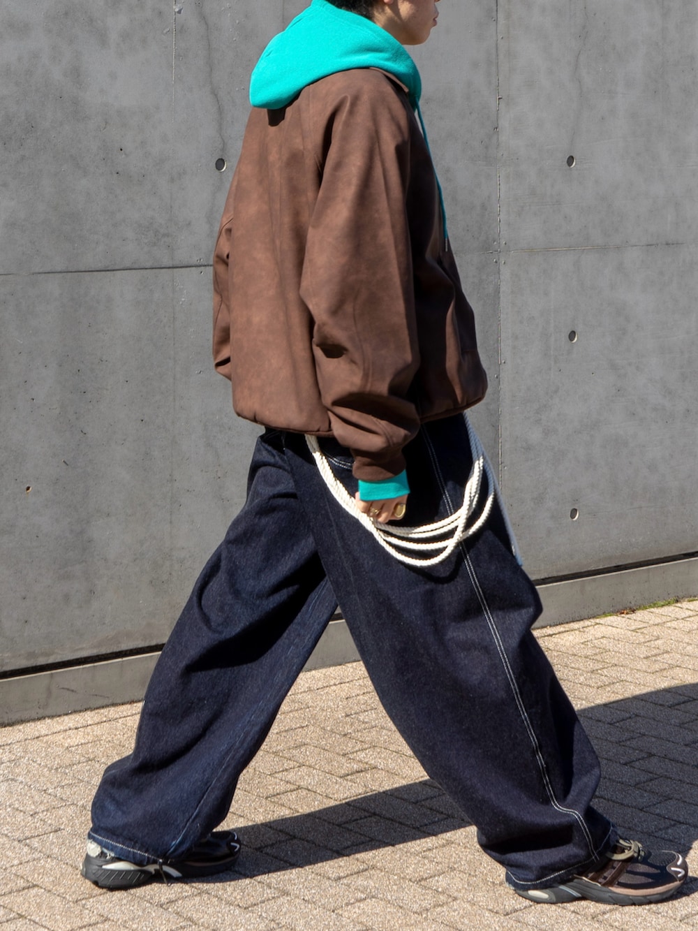 ブラウン系のブルゾン、ブルー系のパーカー、ブルー系のデニムパンツを着用したメンズの秋コーディネートの5枚目の写真