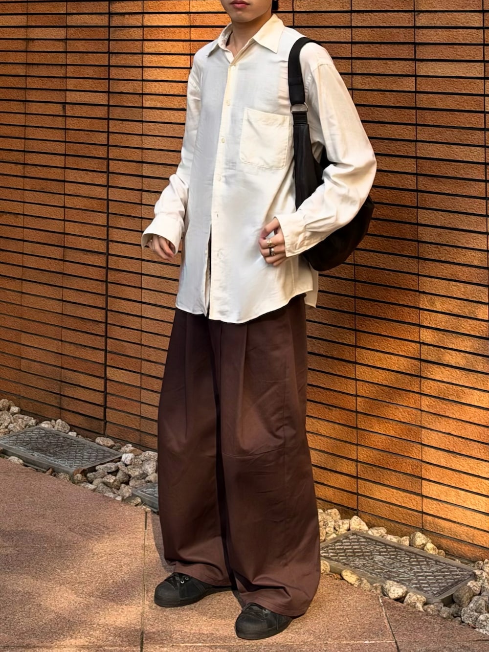 ブラウン系のショルダーバッグ、ブラウン系のその他パンツ、ブラック系のスニーカーを着用したメンズの秋コーディネートの3枚目の写真