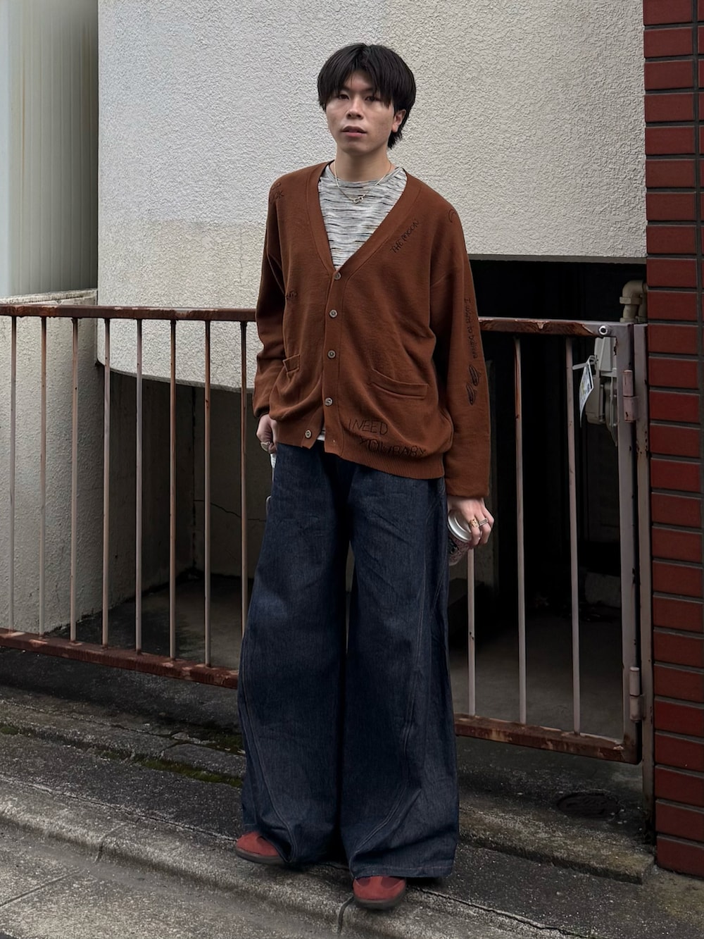 ブラウン系のカーディガン/ボレロ、グレー系のTシャツ/カットソー、ブルー系のデニムパンツを着用したメンズの春コーディネートの2枚目の写真