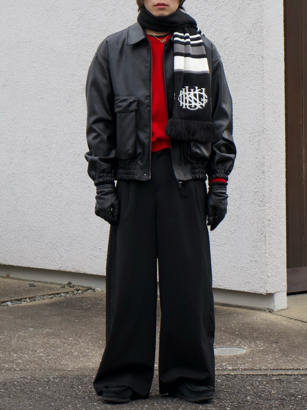 ブラック系のブルゾン、レッド系のニット/セーター、ブラック系のスラックスを着用したメンズの冬コーディネートの5枚目の写真