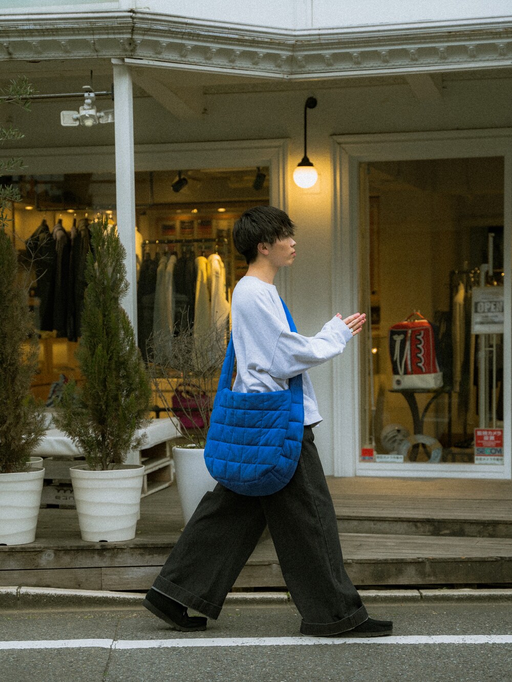 グレー系のスウェット、ブラック系のデニムパンツ、ブルー系のショルダーバッグを着用したメンズの春コーディネートの3枚目の写真
