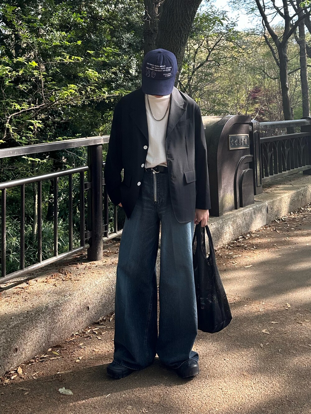 ブラック系のテーラードジャケット、ブルー系のデニムパンツ、ブラック系のショルダーバッグを着用したメンズの春コーディネートの2枚目の写真