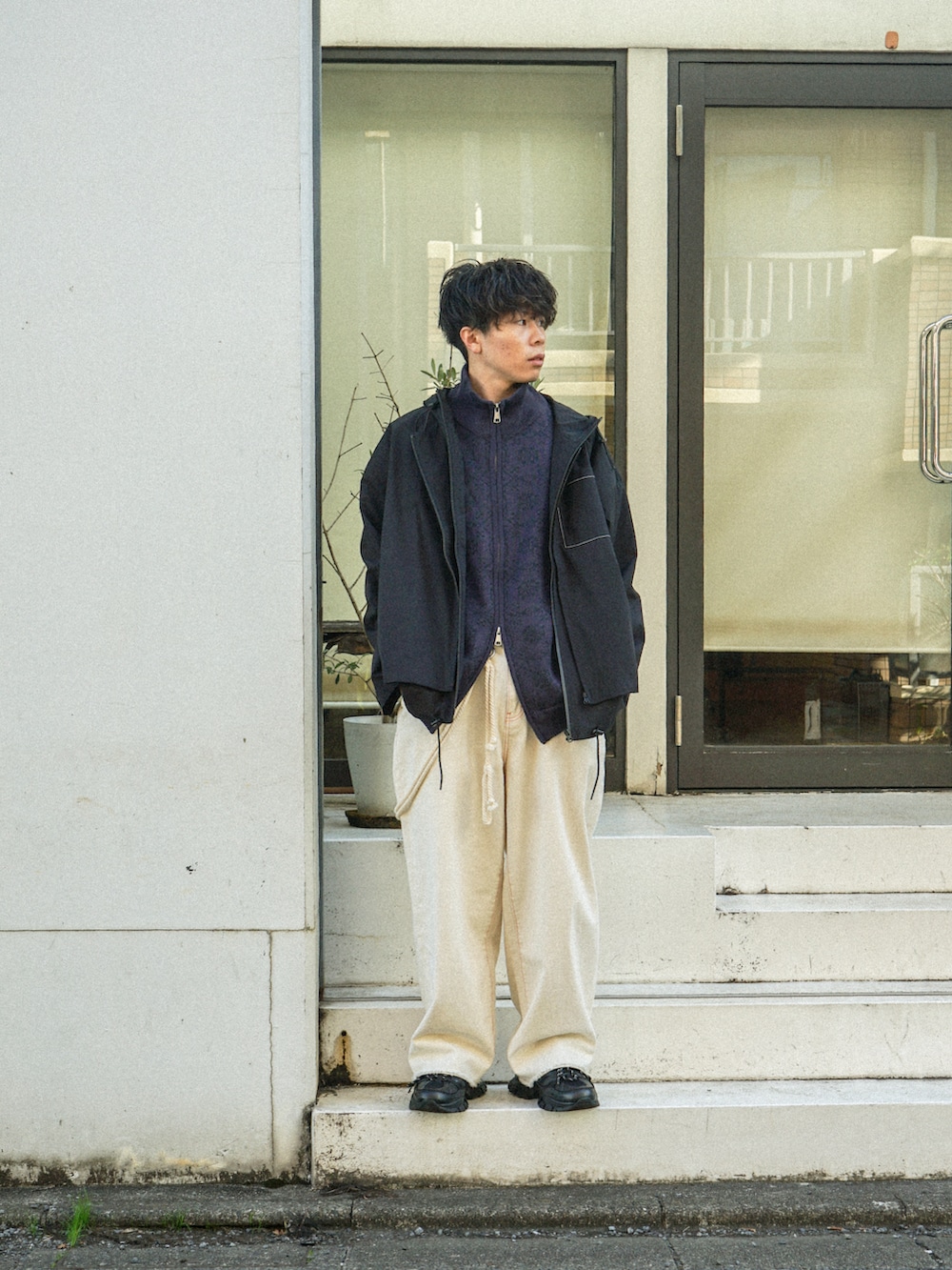 ブラック系のマウンテンパーカー、パープル系のニット/セーター、ブラック系のデニムパンツを着用したメンズの冬コーディネートの3枚目の写真