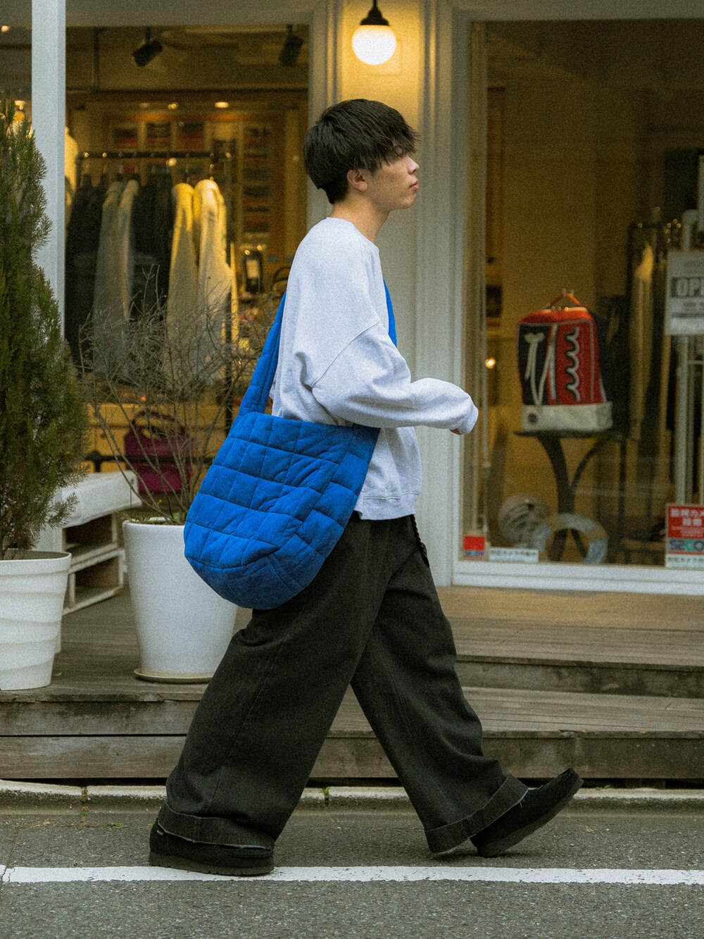 グレー系のスウェット、ブラック系のデニムパンツ、ブルー系のショルダーバッグを着用したメンズの春コーディネートの2枚目の写真