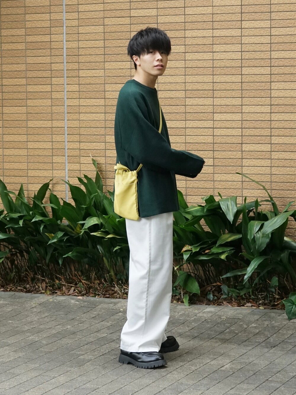 グリーン系のニット/セーター、ホワイト系のチノパンツ、イエロー系のショルダーバッグを着用したメンズの秋コーディネートの3枚目の写真