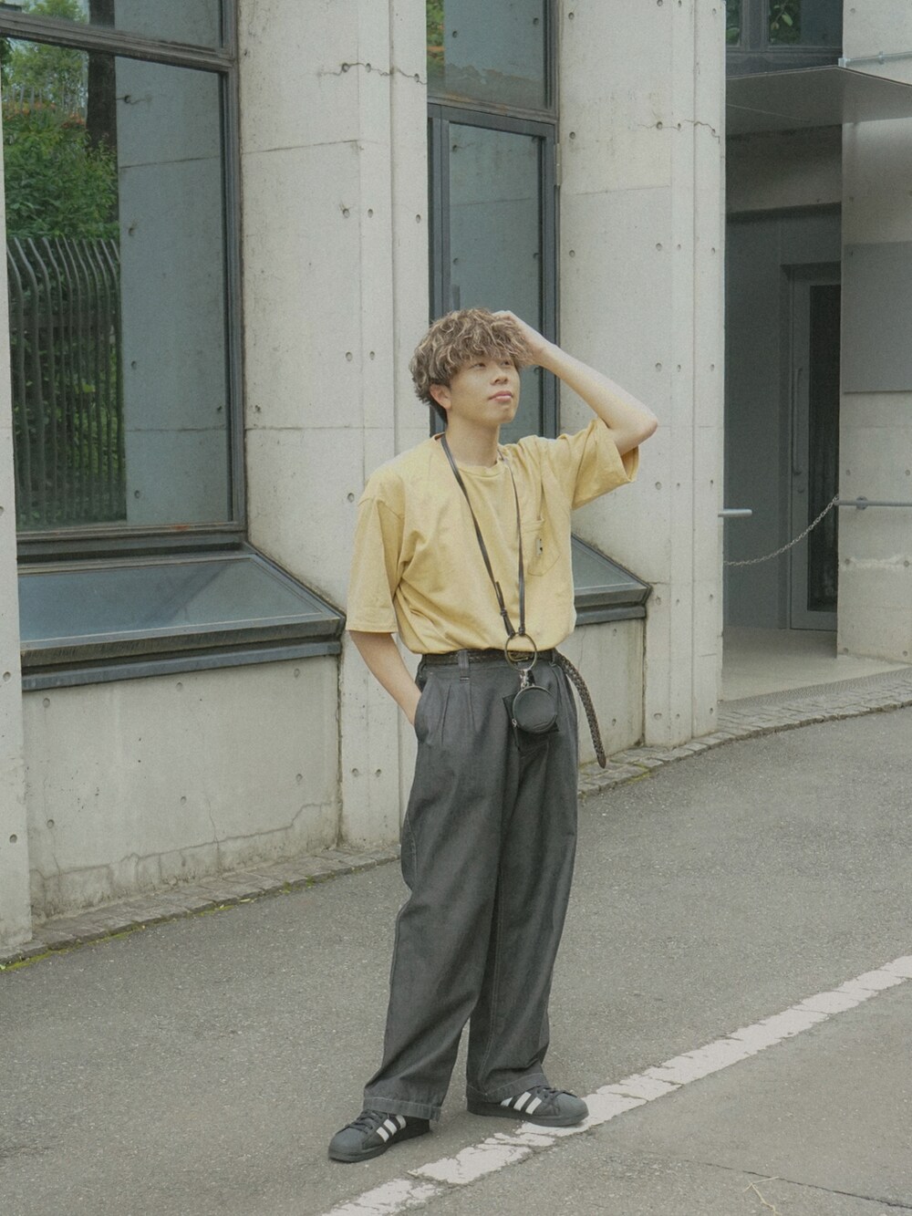 イエロー系のTシャツ/カットソー、グレー系のデニムパンツ、ブラック系のショルダーバッグを着用したメンズの春コーディネートの3枚目の写真