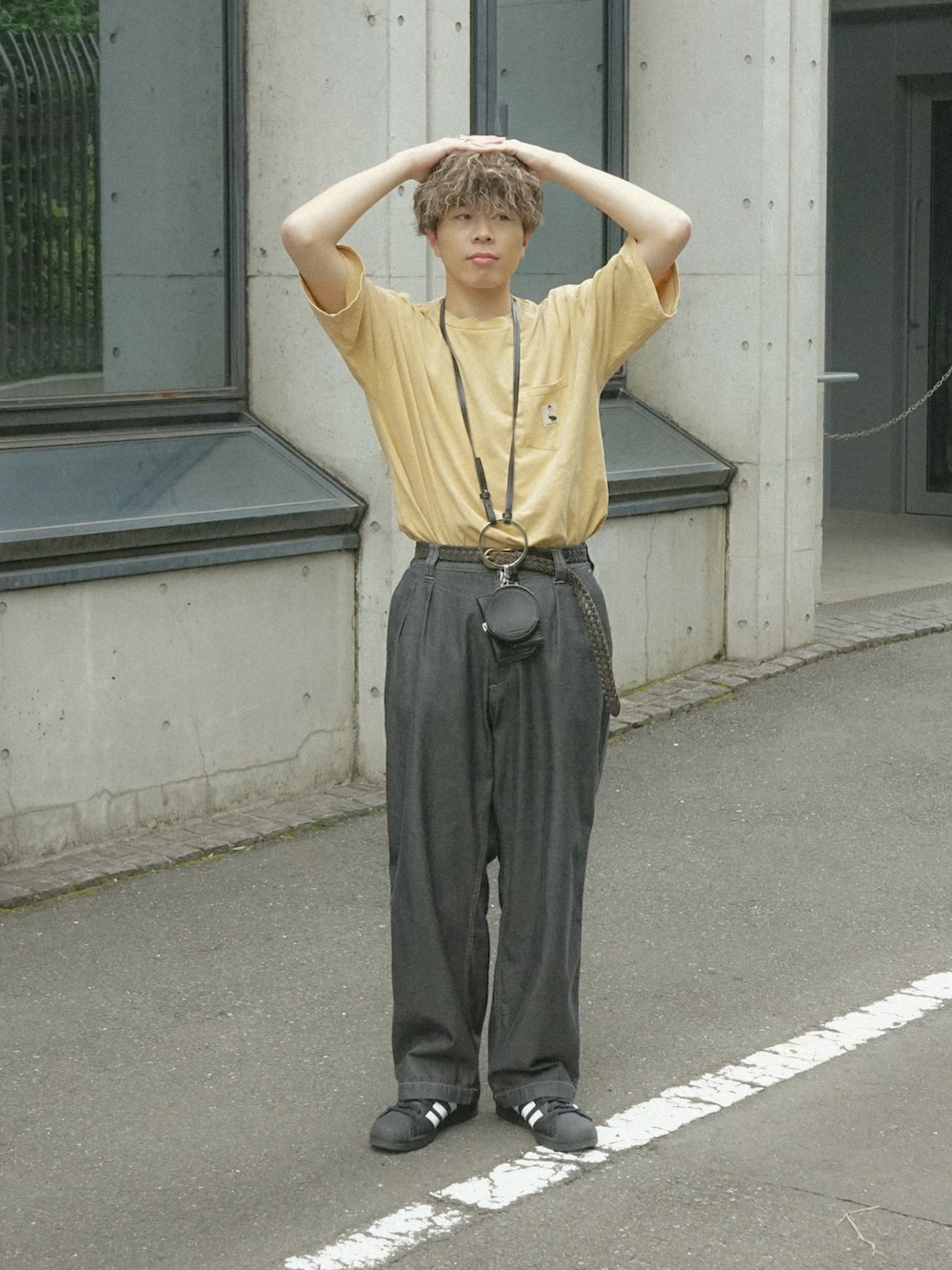 イエロー系のTシャツ/カットソー、グレー系のデニムパンツ、ブラック系のショルダーバッグを着用したメンズの春コーディネートの2枚目の写真