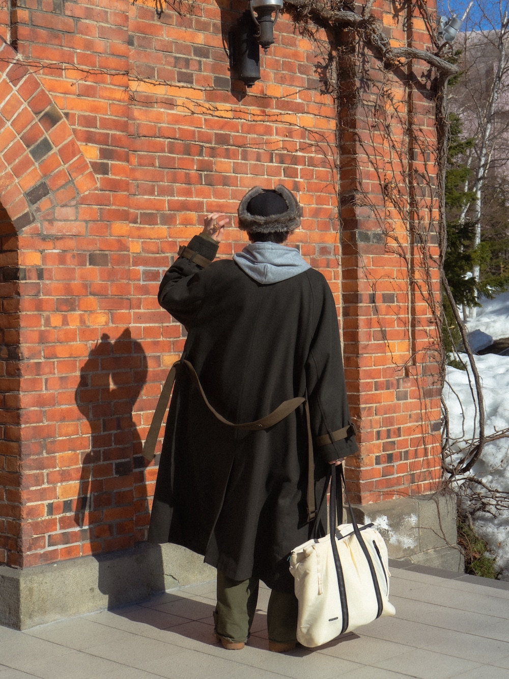 グリーン系のステンカラーコート、グレー系のパーカー、ブラック系のカバーオールを着用したメンズの春コーディネートの3枚目の写真