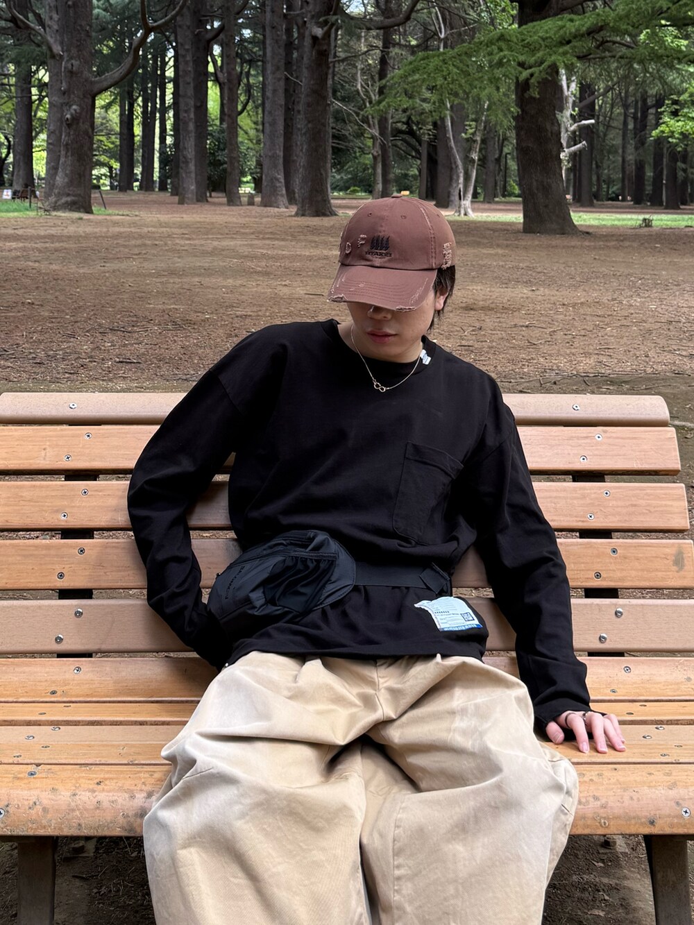 ブラック系のTシャツ/カットソー、ベージュ系のチノパンツ、ブラック系のボディバッグ/ウエストポーチを着用したメンズの春コーディネートの3枚目の写真