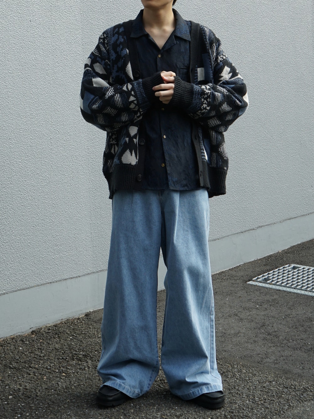 ブルー系のカーディガン/ボレロ、ブルー系のスラックス、ブラック系のブーツを着用したメンズの秋コーディネートの5枚目の写真