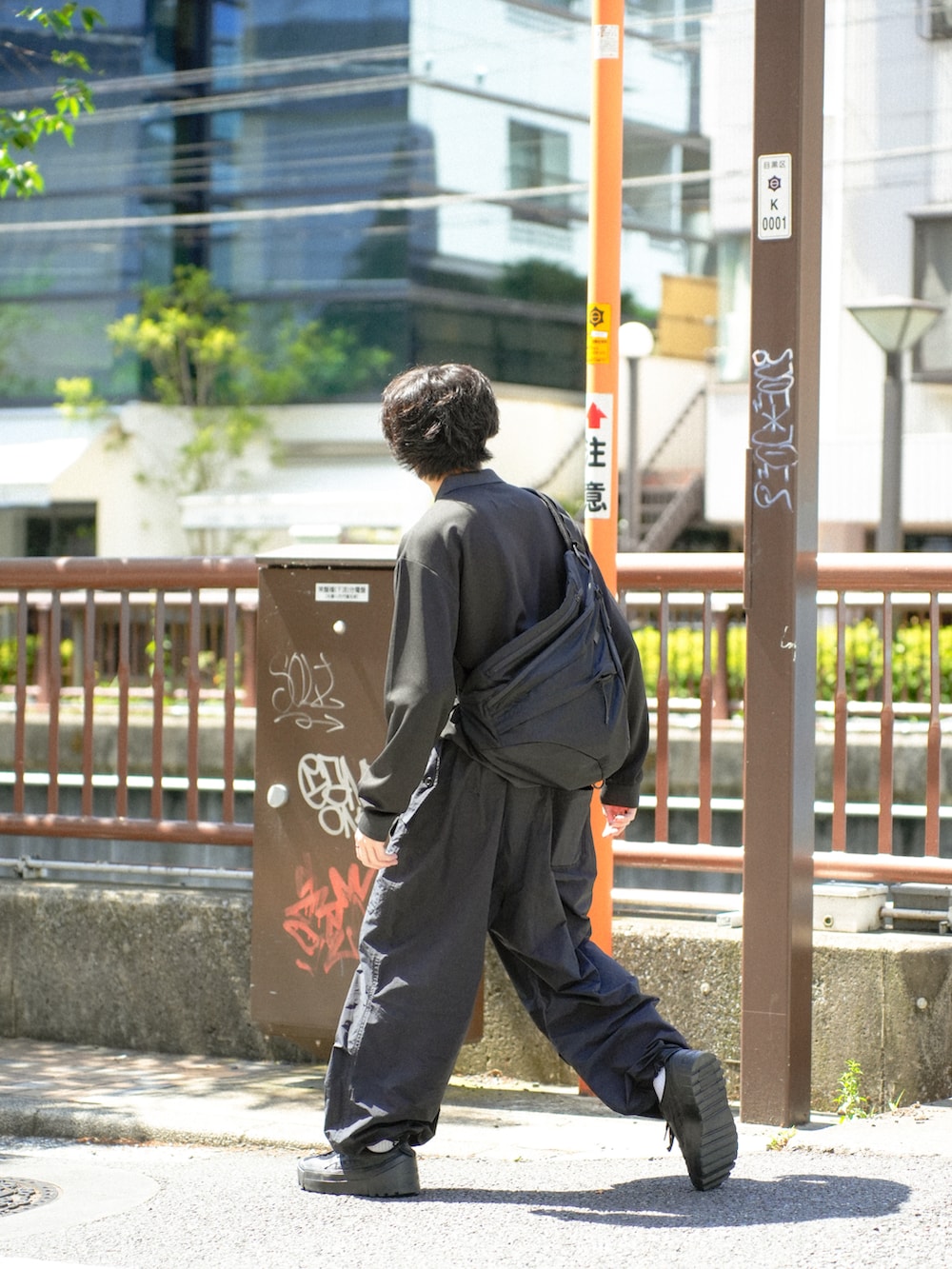 ブラック系のポロシャツ、ブラック系のショルダーバッグ、ブラック系のカーゴパンツを着用したメンズの春コーディネートの3枚目の写真