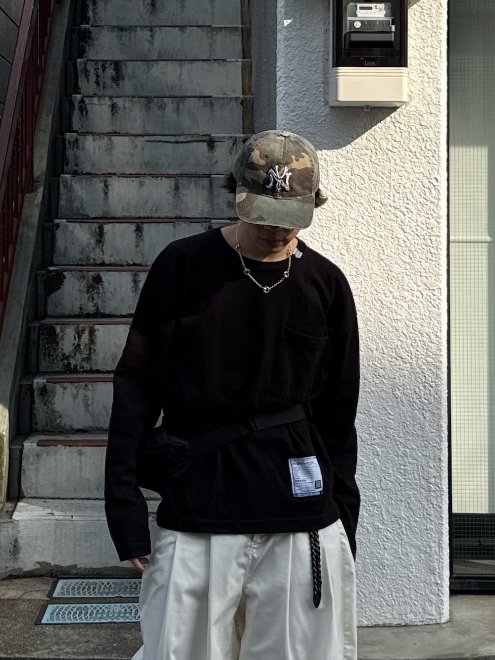 ブラック系のTシャツ/カットソー、ホワイト系のその他パンツ、ブラック系のボディバッグ/ウエストポーチを着用したメンズの春コーディネートの4枚目の写真