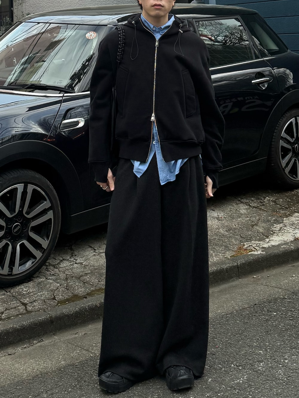 ブラック系のパーカー、グレー系のスラックス、ブラック系のショルダーバッグを着用したメンズの冬コーディネートの4枚目の写真