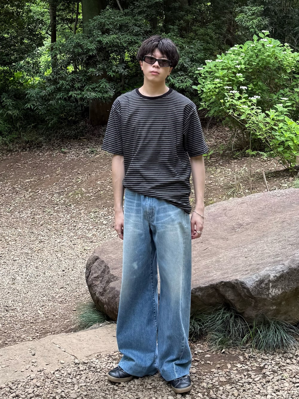 ブラック系のTシャツ/カットソー、ブルー系のデニムパンツ、ブラック系のスニーカーを着用したメンズの春コーディネートの3枚目の写真
