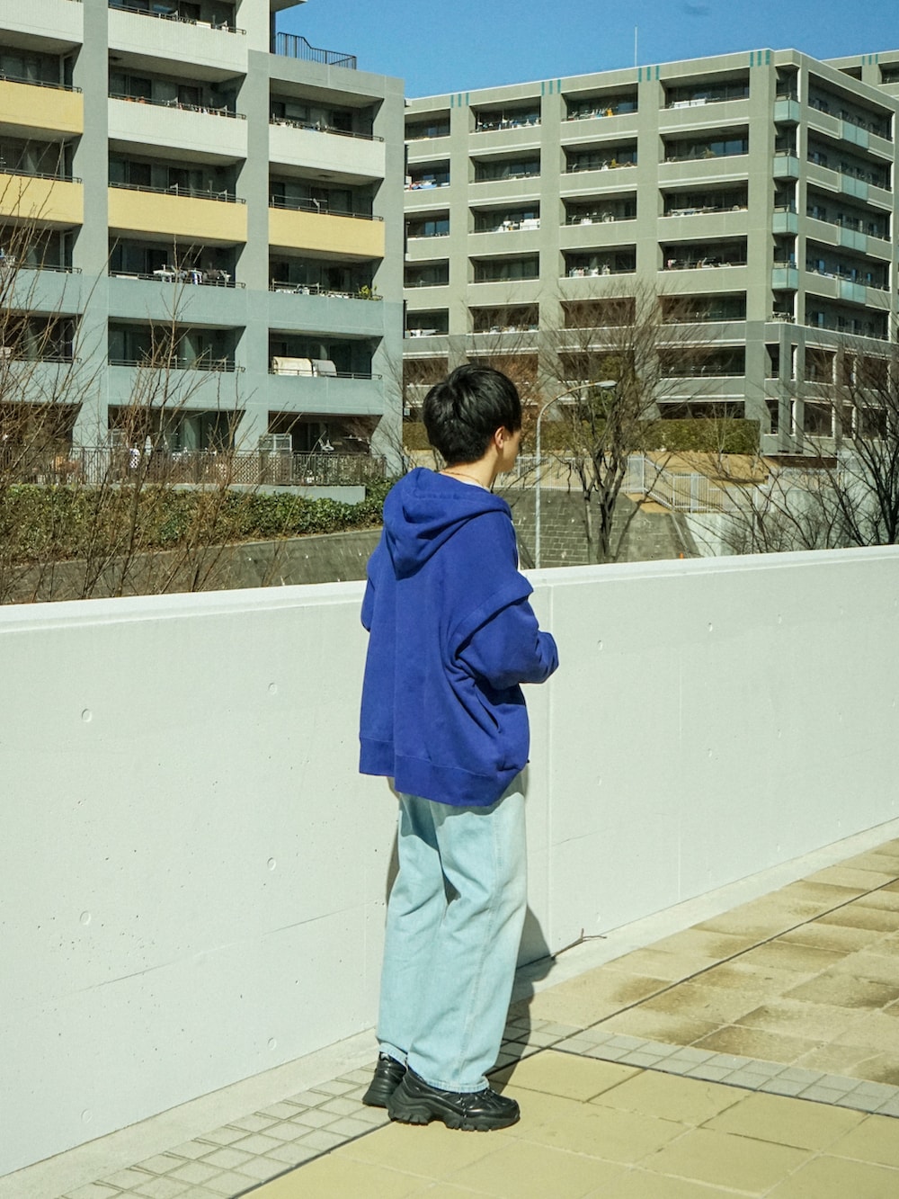 ブルー系のパーカー、ブルー系のデニムパンツ、ブラック系のスニーカーを着用したメンズの冬コーディネートの4枚目の写真