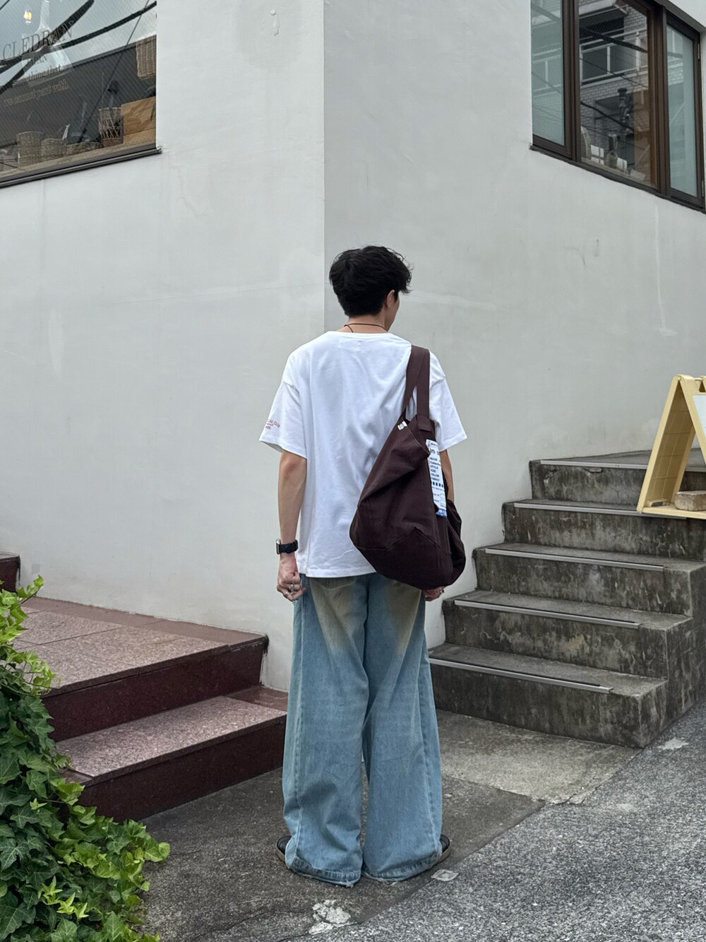ホワイト系のTシャツ/カットソー、ブルー系のデニムパンツ、ブラウン系のトートバッグを着用したメンズの夏コーディネートの3枚目の写真