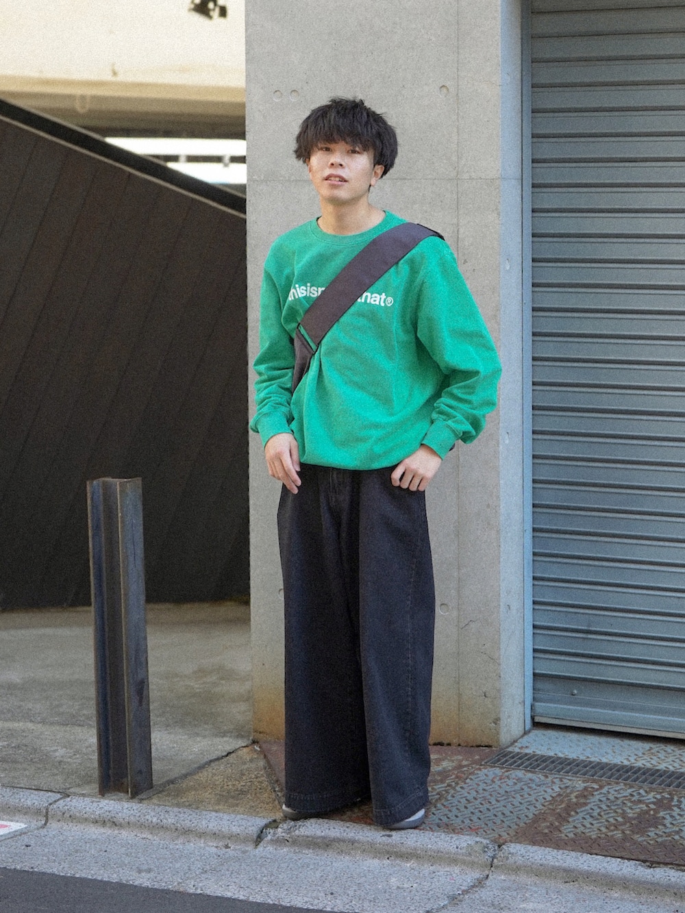 グリーン系のスウェット、ブラック系のデニムパンツ、グレー系のショルダーバッグを着用したメンズの冬コーディネートの2枚目の写真