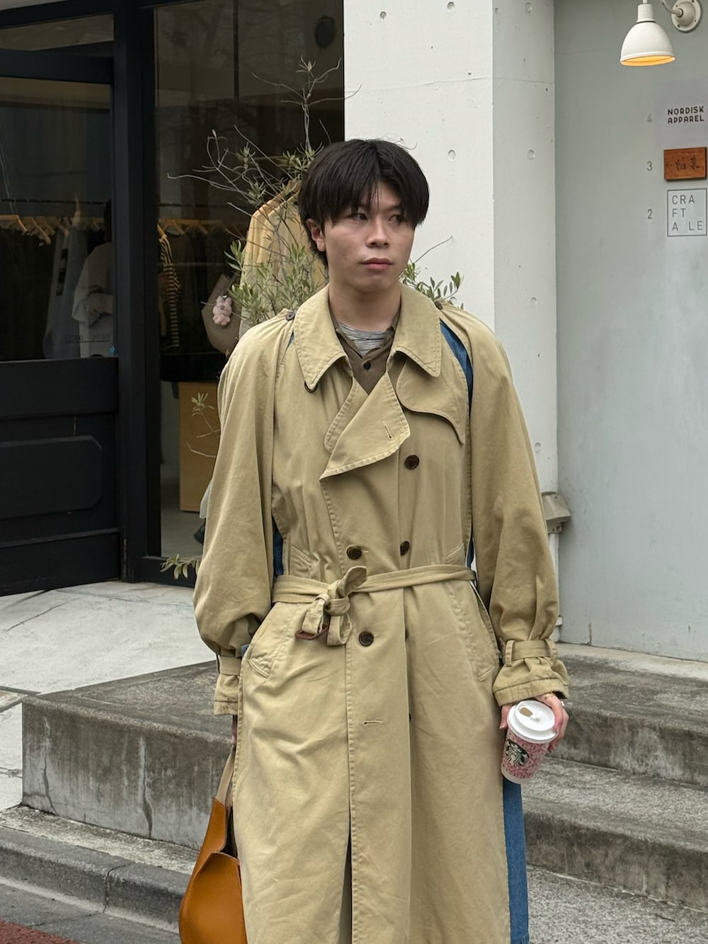 ベージュ系のトレンチコート、グリーン系のシャツ/ブラウス、グレー系のTシャツ/カットソーを着用したメンズの春コーディネートの3枚目の写真