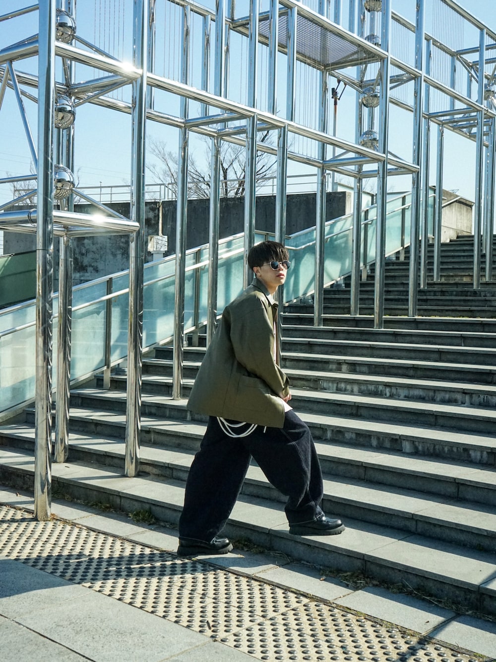 グリーン系のカバーオール、レッド系のシャツ/ブラウス、ブルー系のデニムパンツを着用したメンズの春コーディネートの4枚目の写真