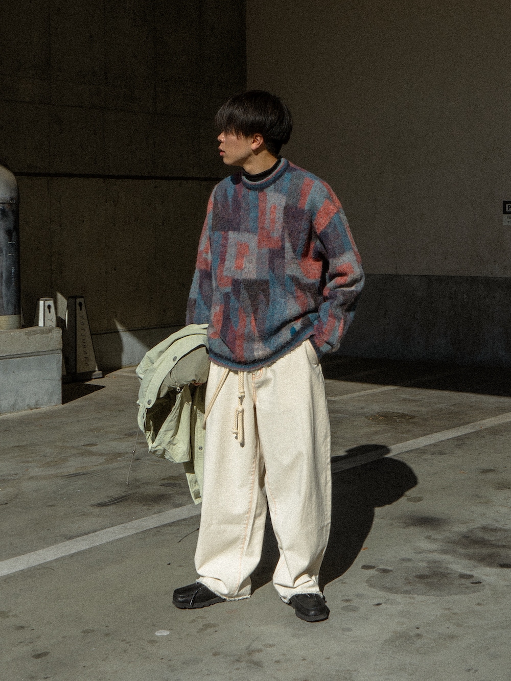 ブルー系のニット/セーター、ベージュ系のマウンテンパーカー、ブラック系のデニムパンツを着用したメンズの冬コーディネートの2枚目の写真