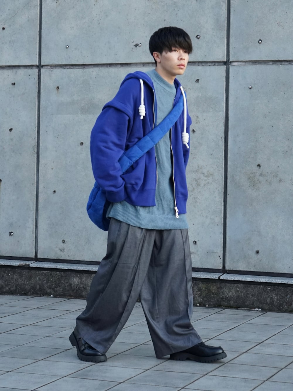 ブルー系のパーカー、ブルー系のニット/セーター、グレー系のスラックスを着用したメンズの秋コーディネートの3枚目の写真