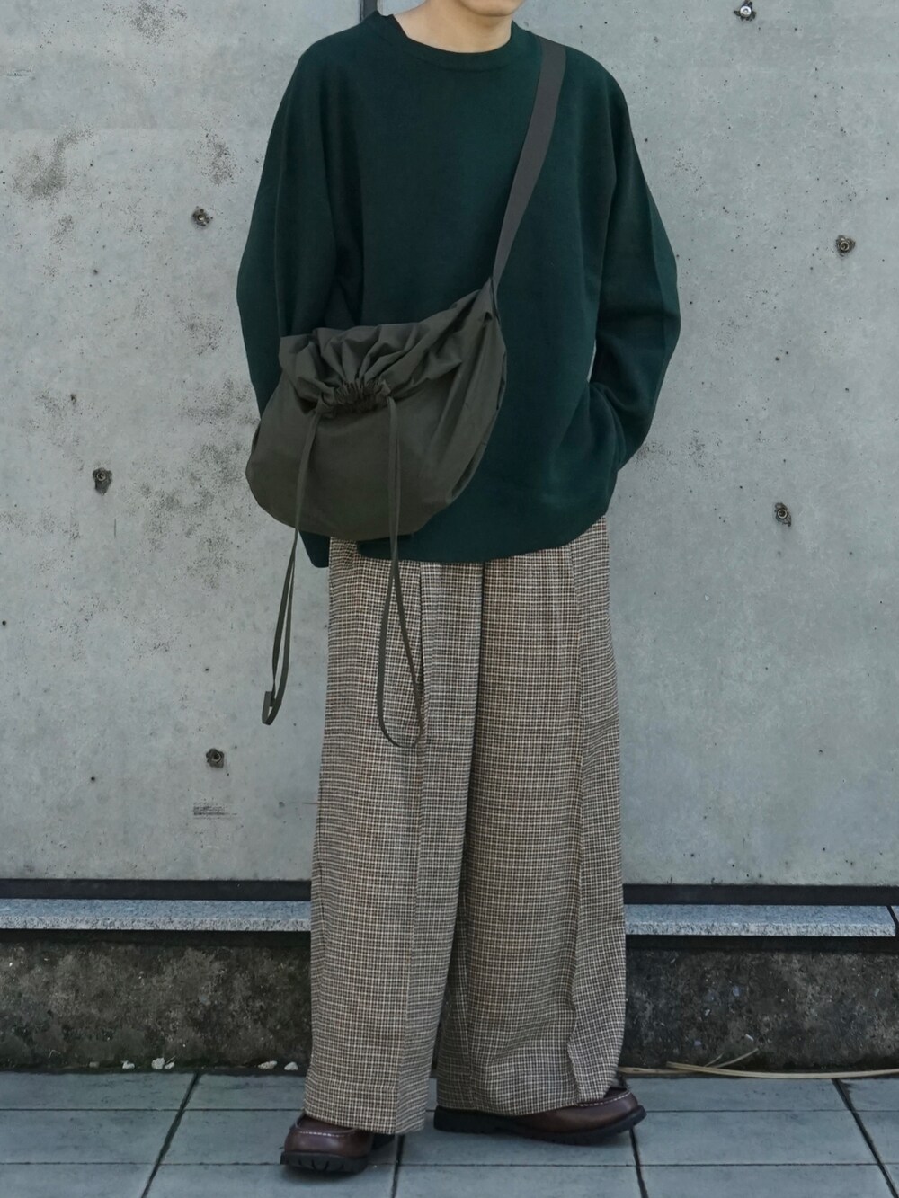 グリーン系のニット/セーター、ベージュ系のスラックス、ブラウン系のモカシン/デッキシューズを着用したメンズの秋コーディネートの5枚目の写真