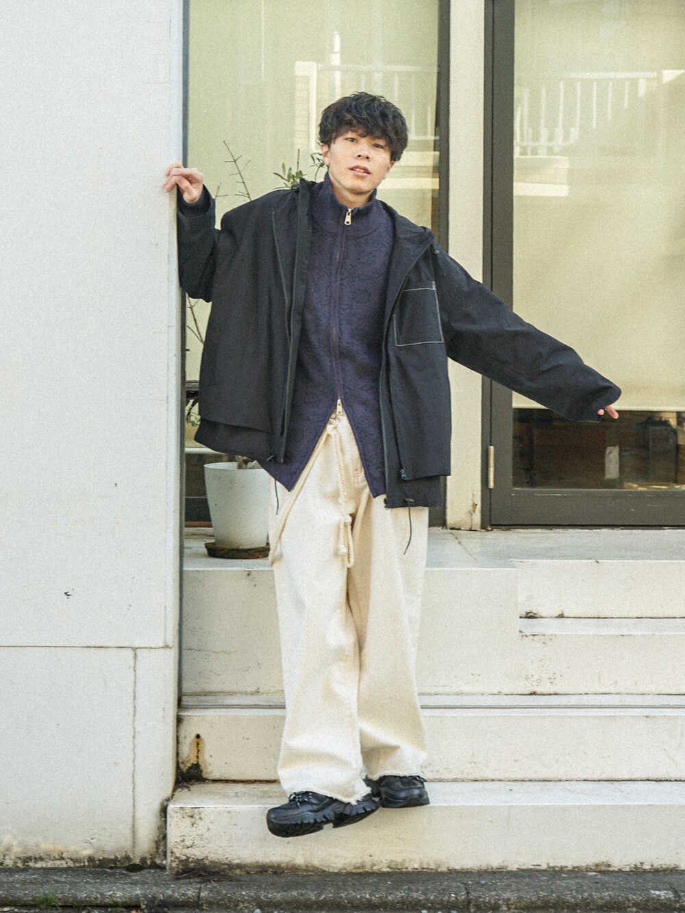 ブラック系のマウンテンパーカー、パープル系のニット/セーター、ブラック系のデニムパンツを着用したメンズの冬コーディネートの2枚目の写真