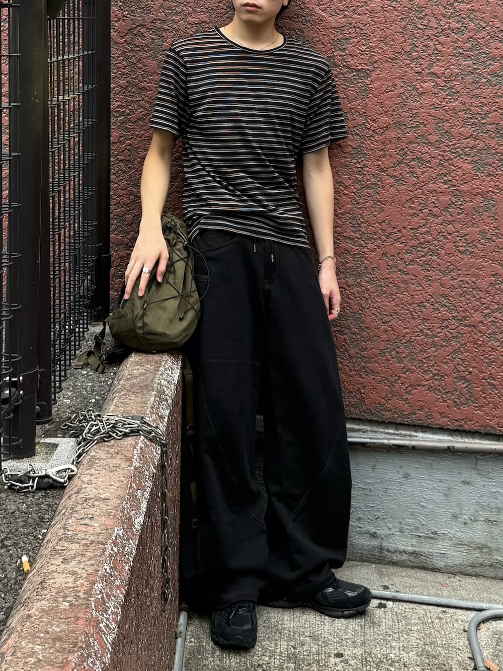 グリーン系のバックパック/リュック、ブラック系のTシャツ/カットソー、ブラック系のスウェットパンツを着用したメンズの秋コーディネートの4枚目の写真