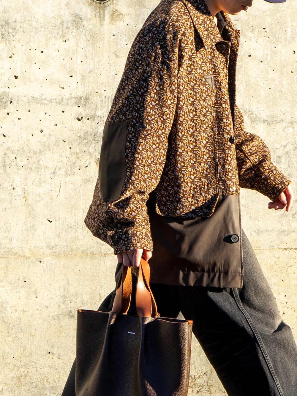 ブラック系のスウェット、ブラウン系のハンドバッグ、ブラック系のデニムパンツを着用したメンズの冬コーディネートの4枚目の写真