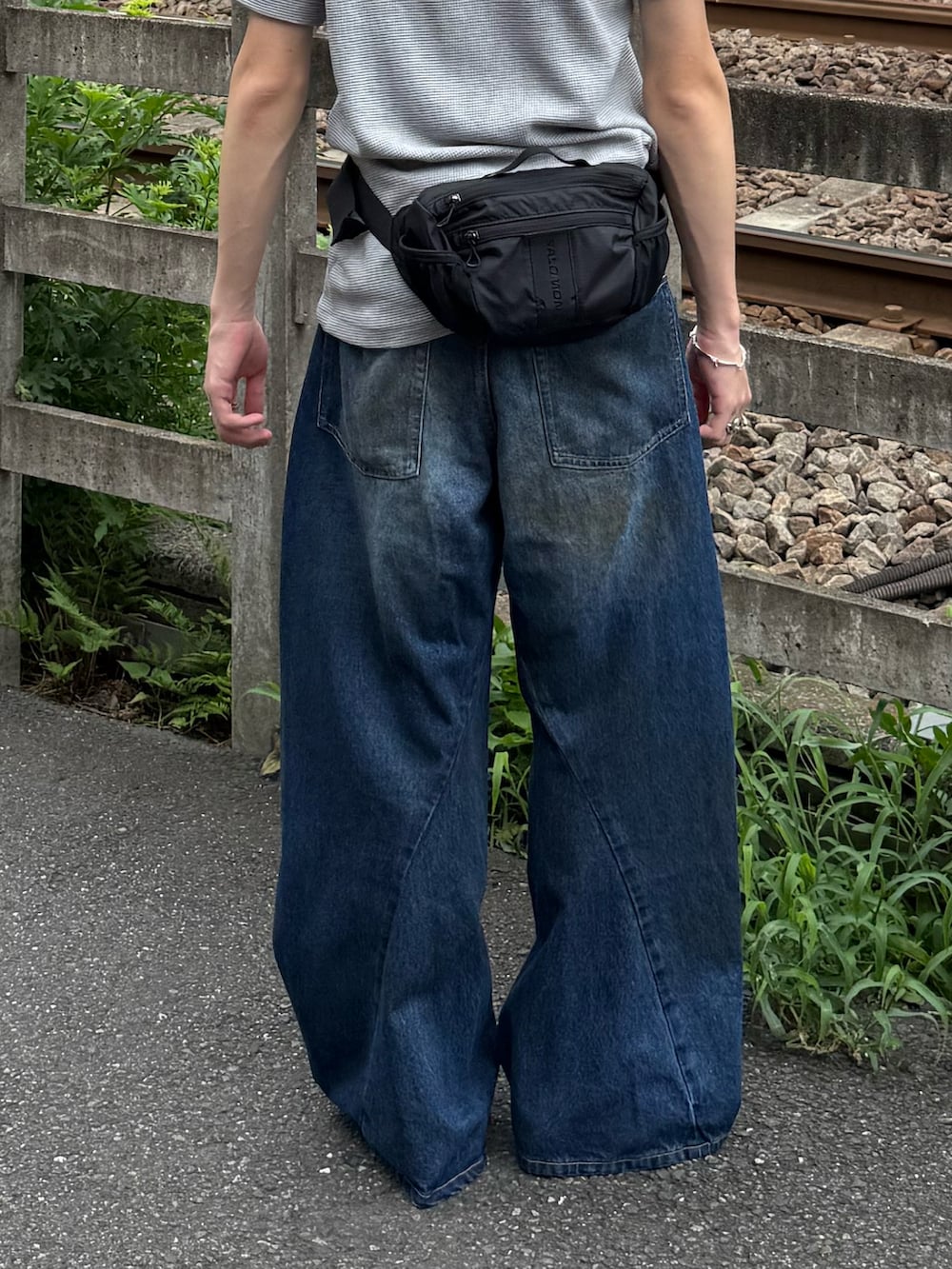 グレー系のTシャツ/カットソー、ブルー系のデニムパンツ、ブラック系のボディバッグ/ウエストポーチを着用したメンズの夏コーディネートの2枚目の写真