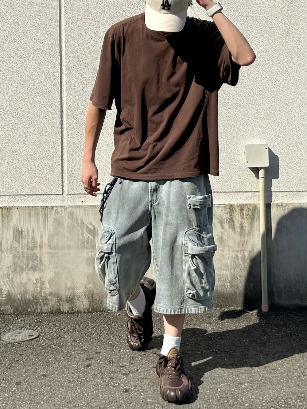 ブラウン系のTシャツ/カットソー、ブルー系のデニムパンツ、ブラウン系のスニーカーを着用したメンズの夏コーディネートの3枚目の写真