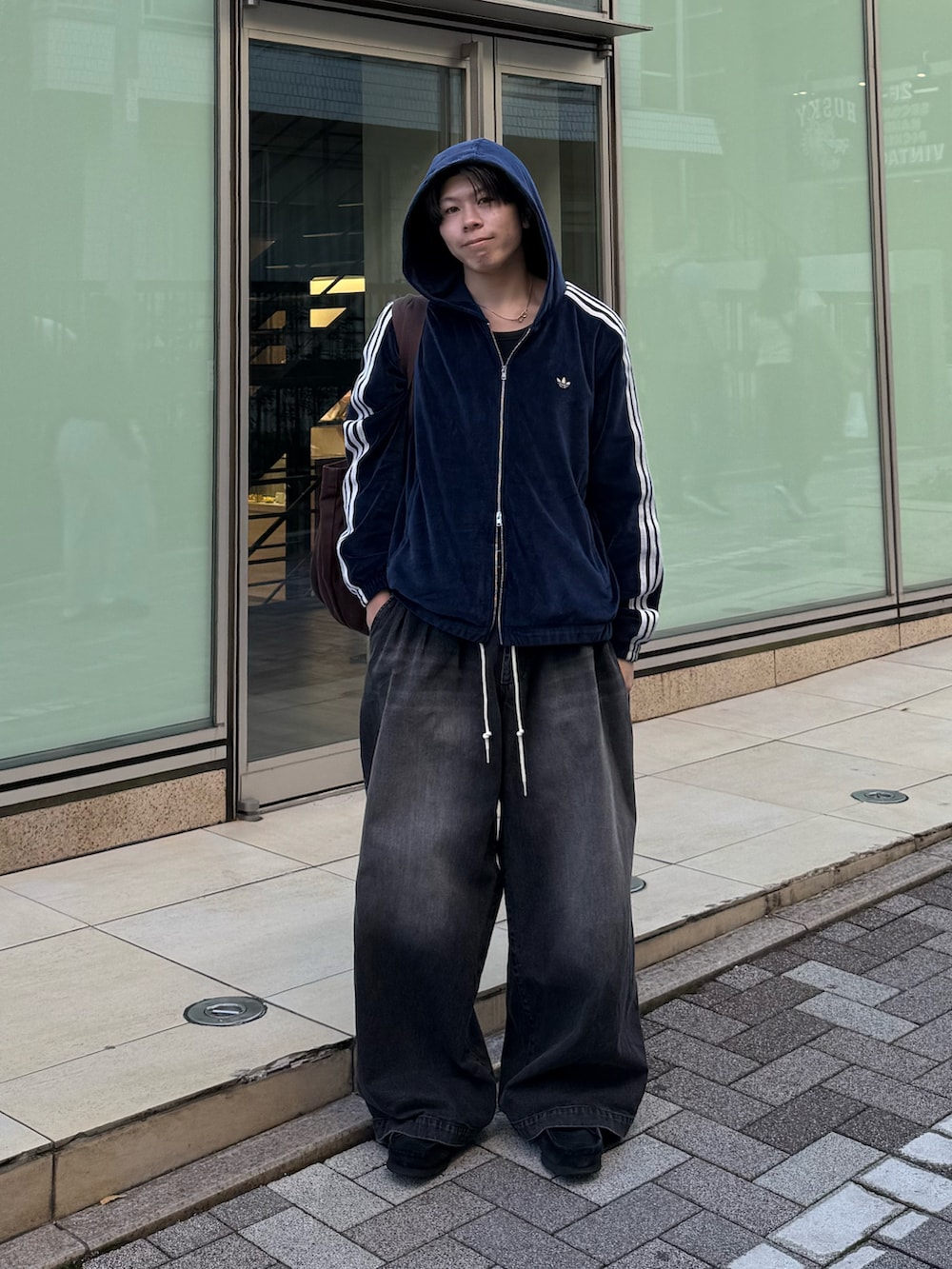 ブルー系のブルゾン、ブラック系のデニムパンツ、ブラウン系のトートバッグを着用したメンズの秋コーディネートの2枚目の写真